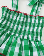 Green and white gingham tiered dress with smocked bodice and red contrast trim, close-up view