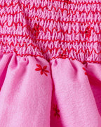 Hot pink baby floral romper dress with red stitched smocking, bodice detail view