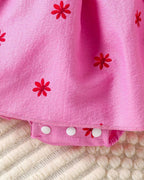 Hot pink baby floral romper dress with three-snap crotch closure, hem detail view