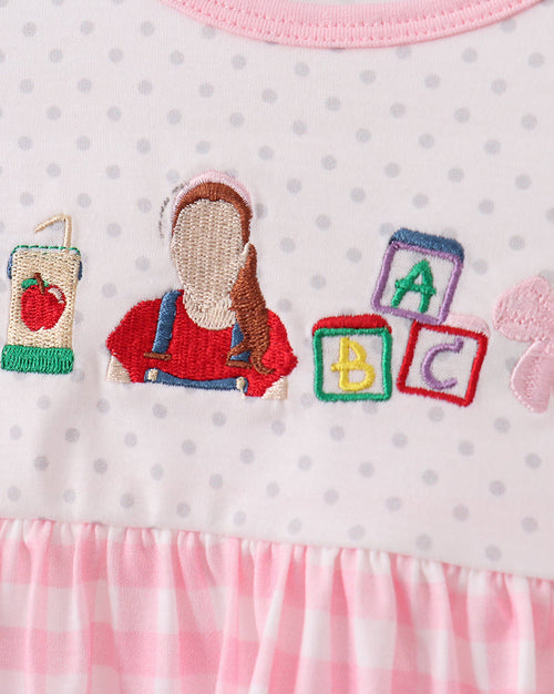 White dotted kids dress bodice with colorful ABC school embroidery, close-up view