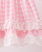 Pink gingham kids dress with layered white eyelet ruffle trim, hem detail view