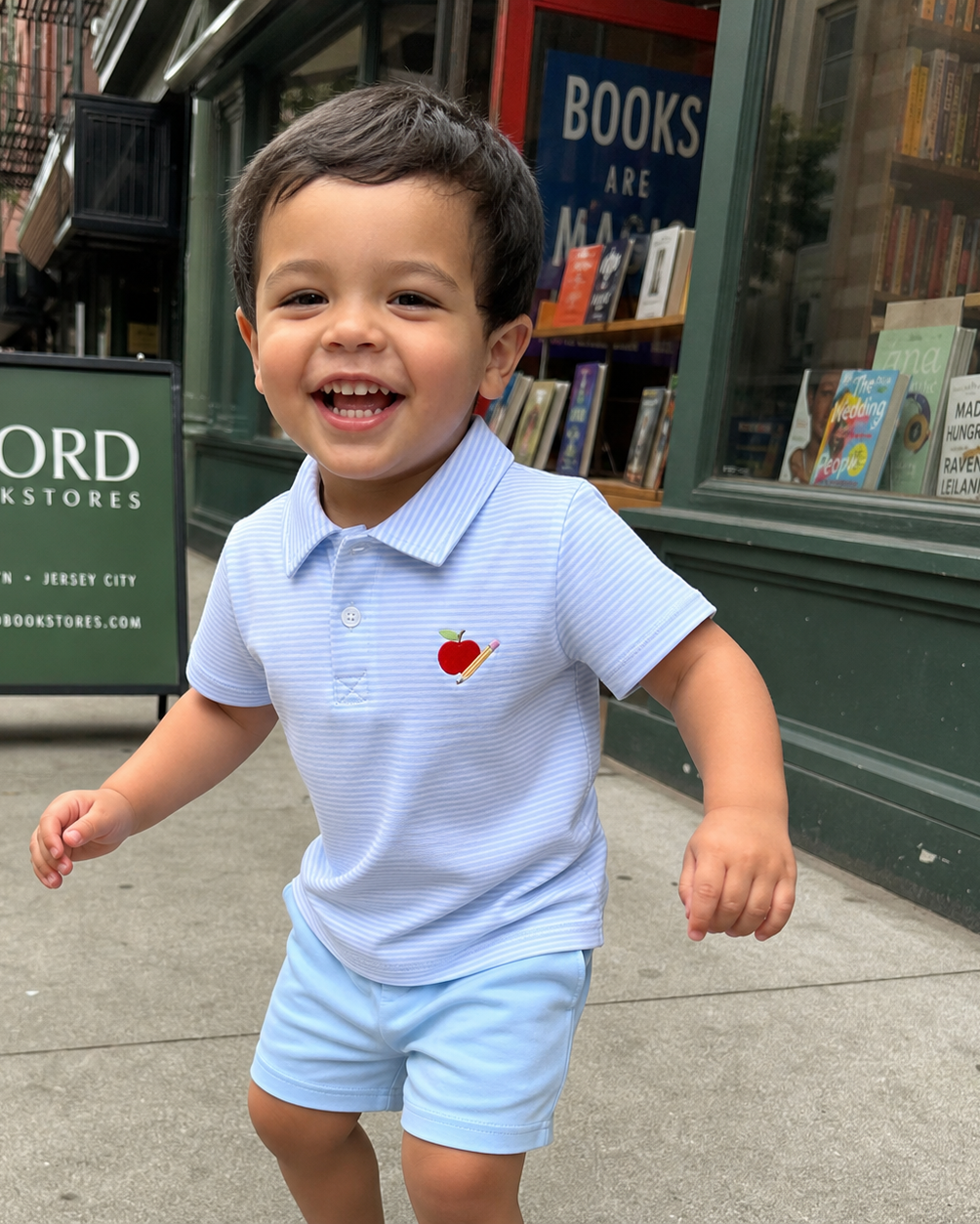 Blue striped kids polo and shorts set with apple and pencil embroidery, front lifestyle view