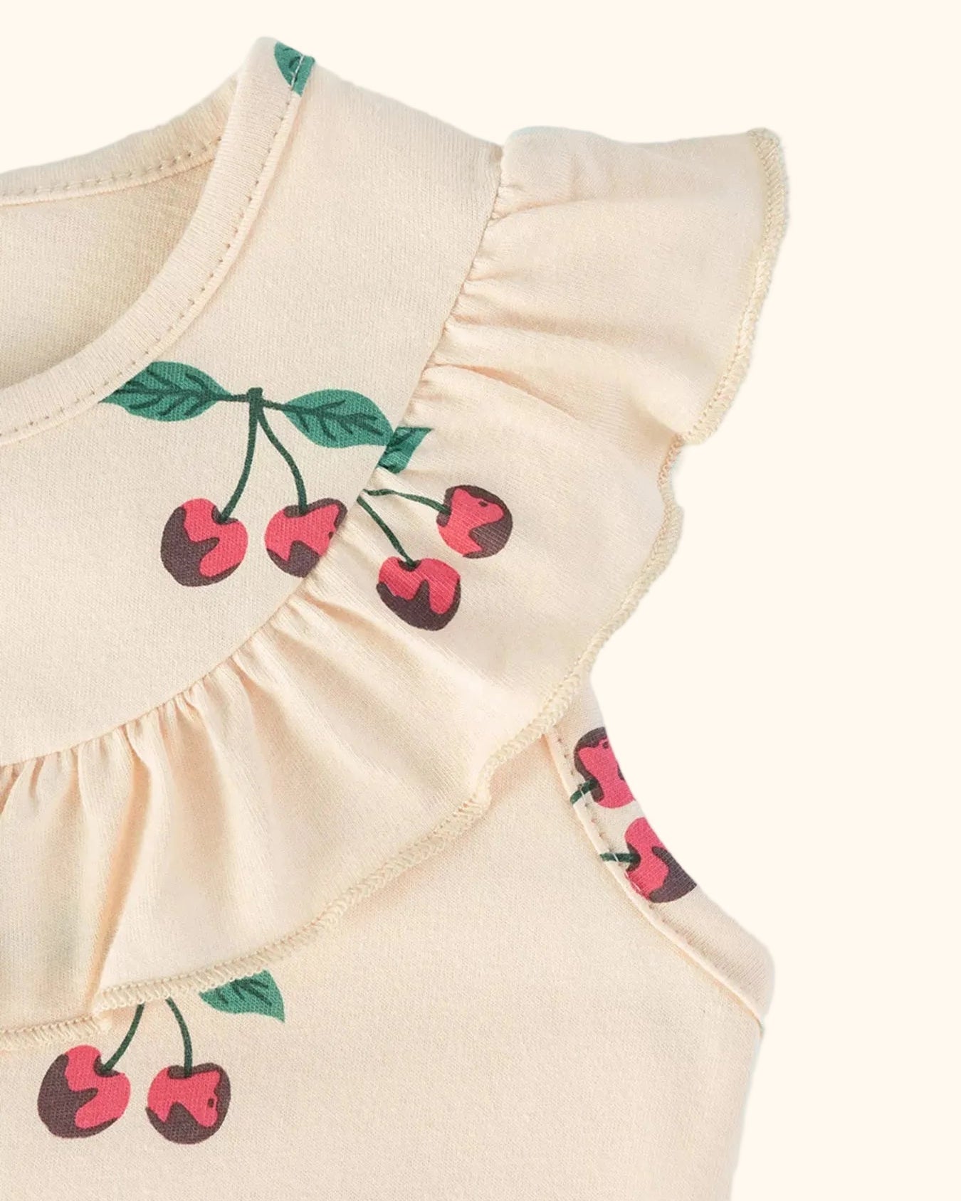 Apricot kids cherry print dress with flutter shoulder and gathered yoke ruffle, close-up view
