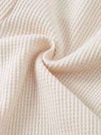 Ivory baby waffle knit fabric with raised textured grid pattern, fabric close-up