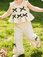 Ivory baby waffle knit bow top and wide-leg pants set with black bows and ruffle trim, modeled front view