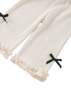 Ivory baby waffle knit wide-leg pants with black bow accents and double ruffle hems, pant-leg close-up