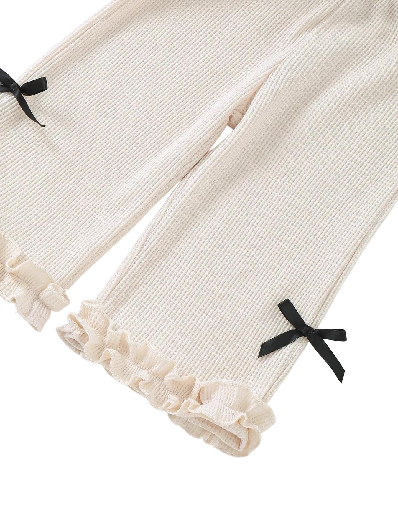Ivory baby waffle knit wide-leg pants with black bow accents and double ruffle hems, pant-leg close-up
