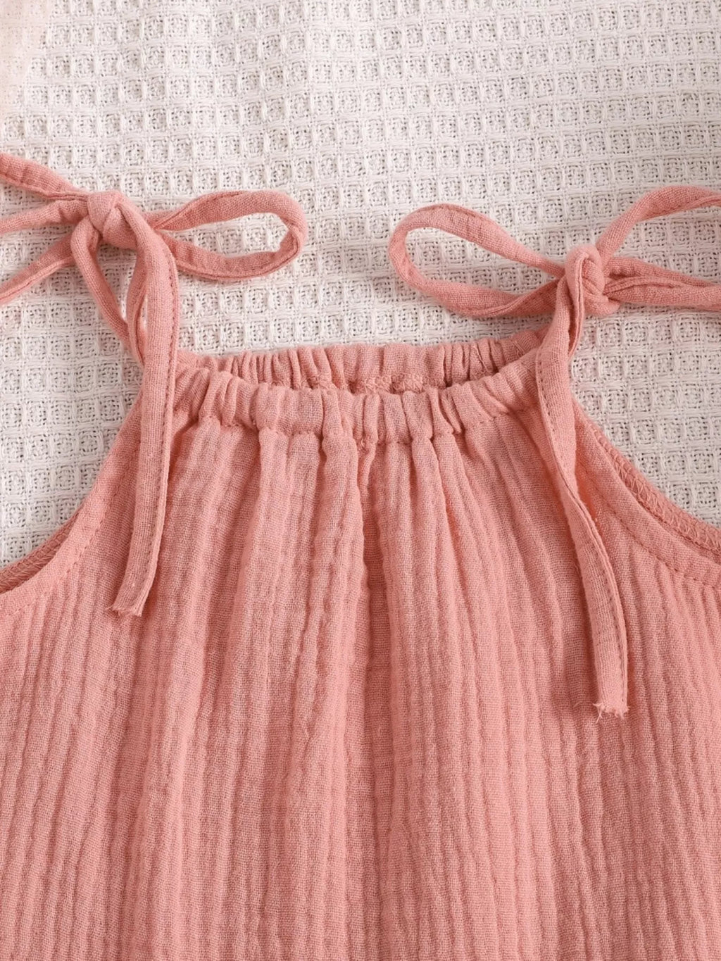 Pink baby textured cami with gathered neckline and tie-shoulder straps, close-up view