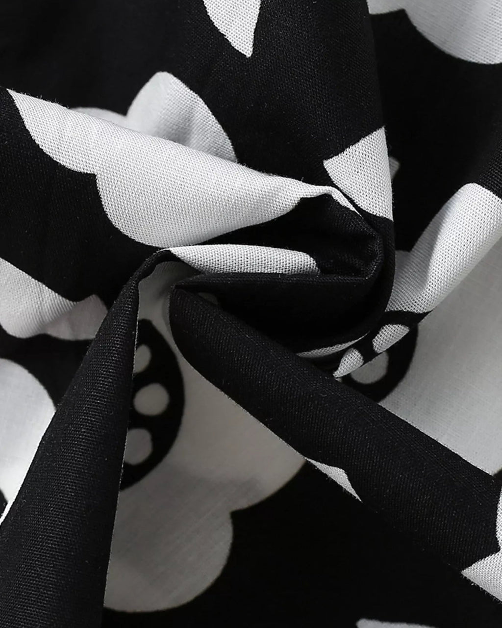 Black and white kids floral dress fabric with oversized flower and leaf print, close-up view