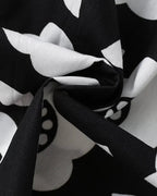 Black and white kids floral dress fabric with oversized flower and leaf print, close-up view