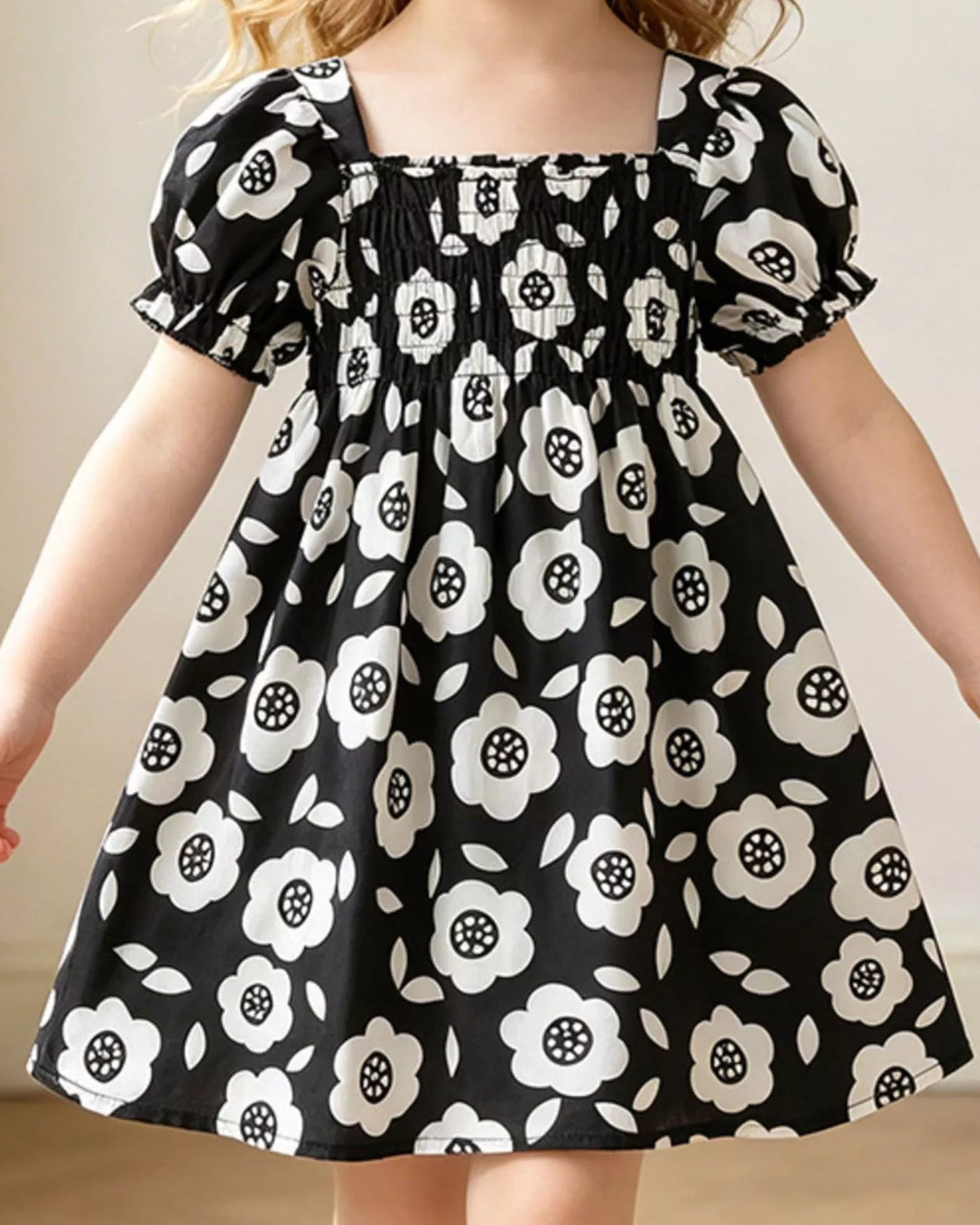 Black kids floral smocked dress with short puff sleeves and gathered skirt, modeled front view