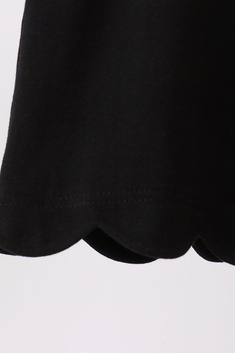 Black kids top with rounded scalloped bottom hem, close-up detail view