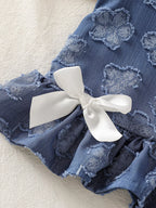 Blue baby flower tank with white bow and gathered ruffle hem, close-up detail view
