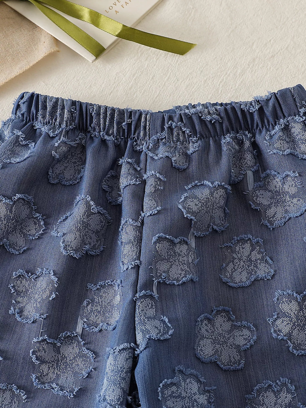 Blue baby wide-leg pants with tonal flower motifs and elastic waistband, close-up view