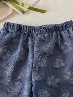 Blue baby wide-leg pants with tonal flower motifs and elastic waistband, close-up view
