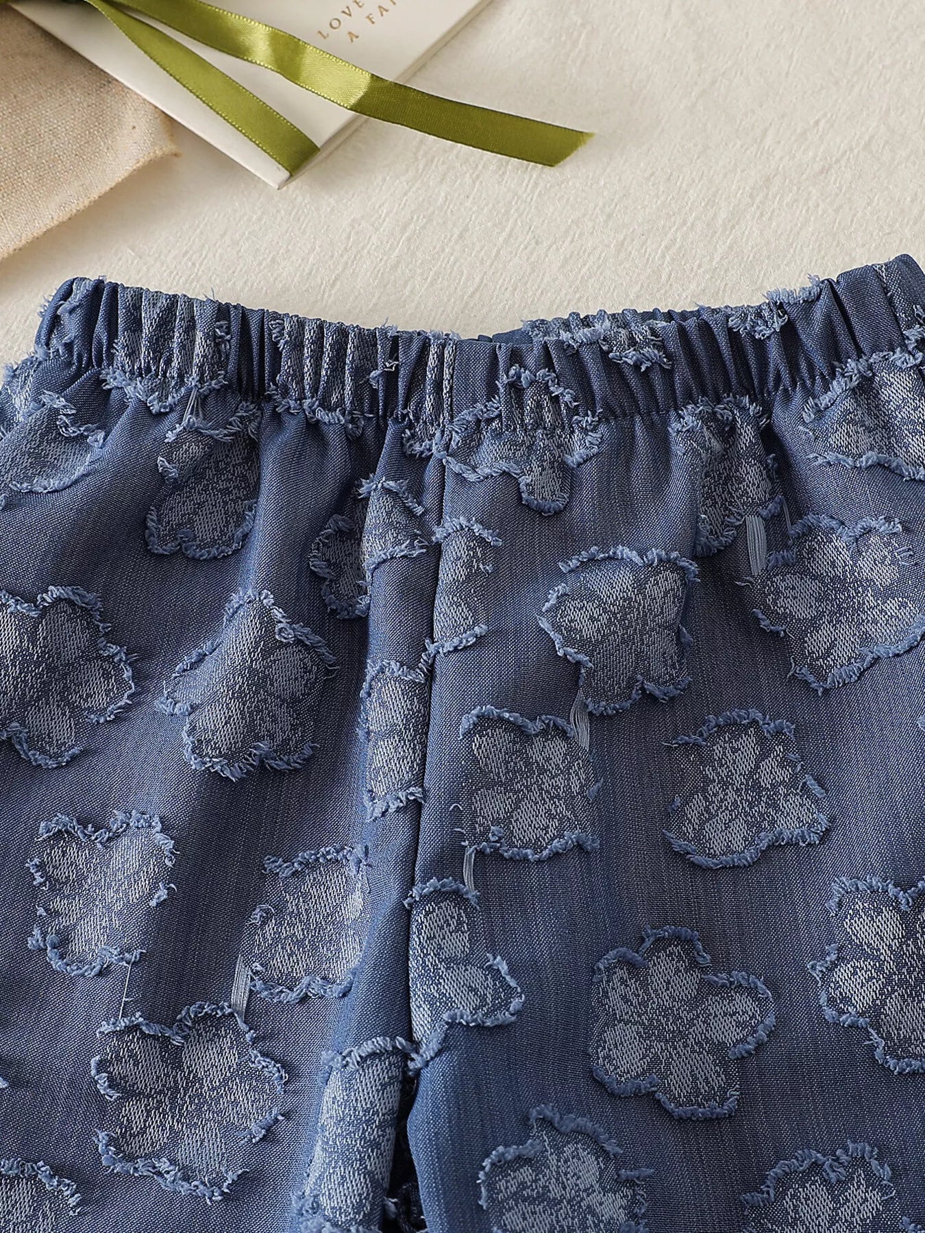 Blue baby wide-leg pants with tonal flower motifs and elastic waistband, close-up view