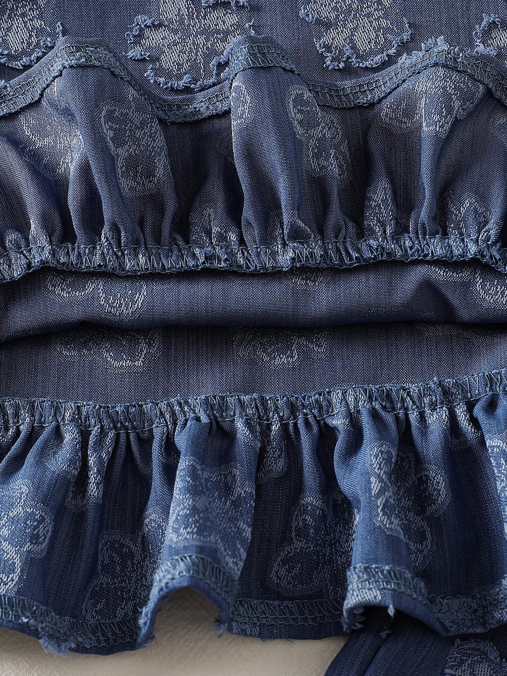 Blue baby flower set with textured tonal floral motifs and gathered ruffle hem, fabric close-up