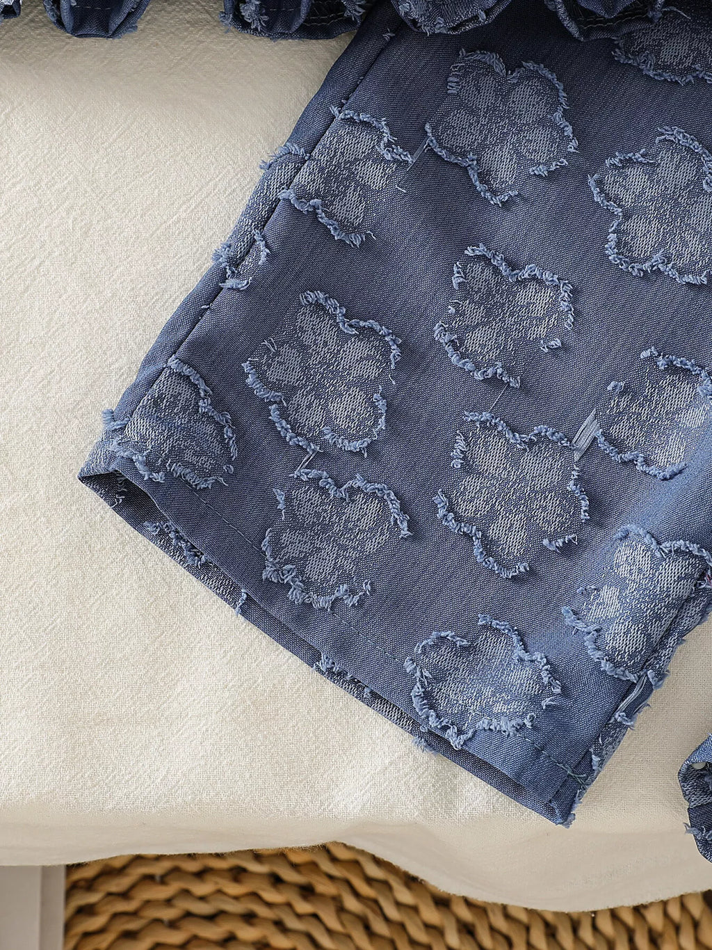 Blue baby wide-leg pants with raised flower motifs and straight hem, leg detail view