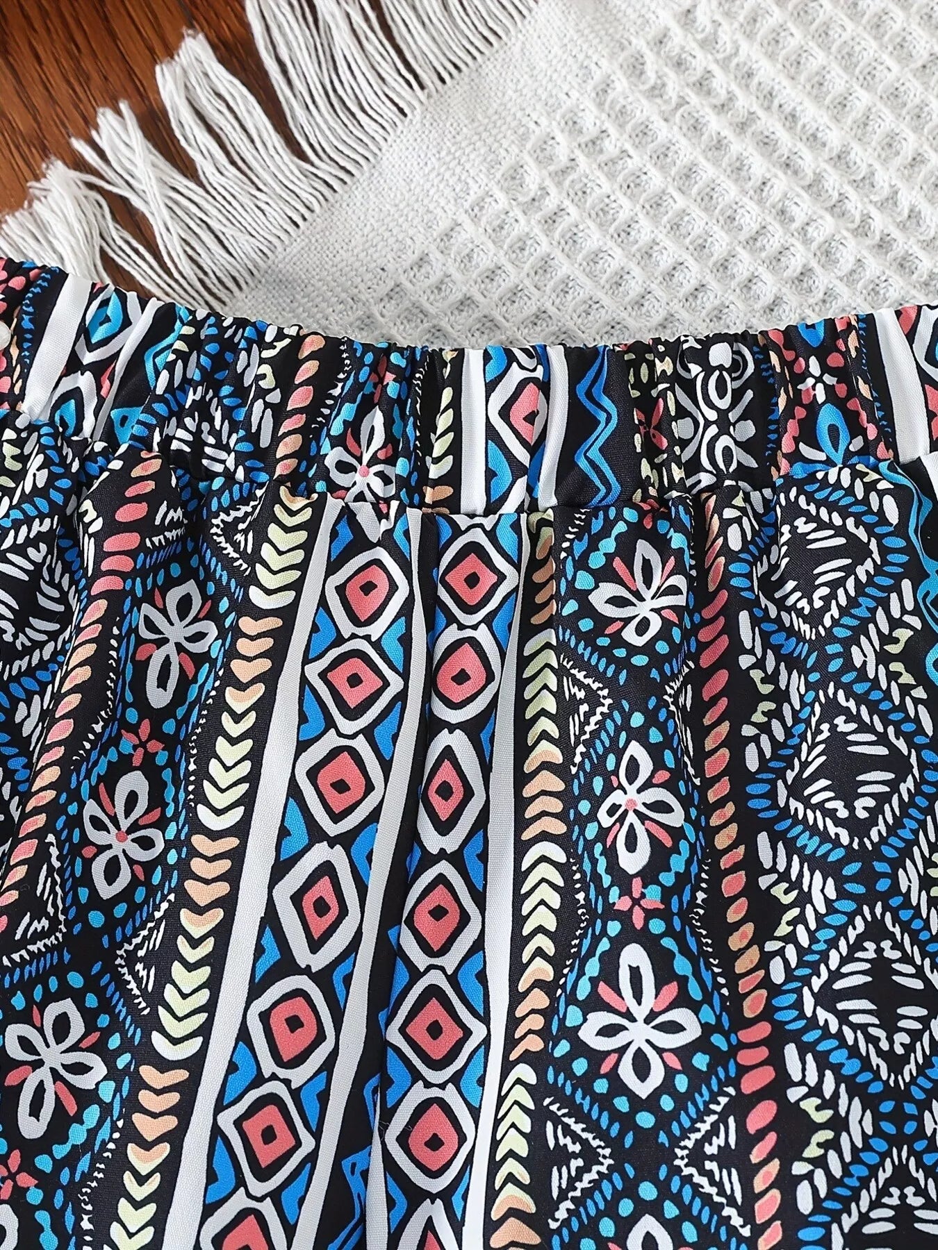 Blue geometric kids wide-leg pants with gathered elastic waistband and pocket, close-up view