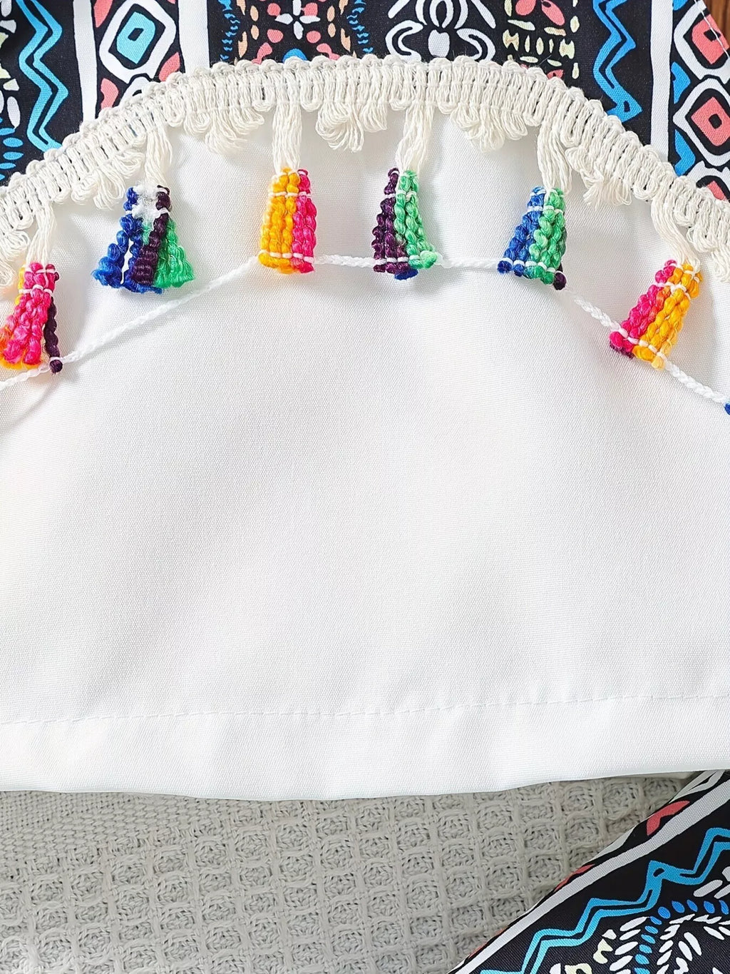 White kids tank with multicolor tassels and curved fringe trim, front detail view