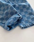 Blue plaid kids tapered trousers with rolled cuff and denim texture, close-up detail