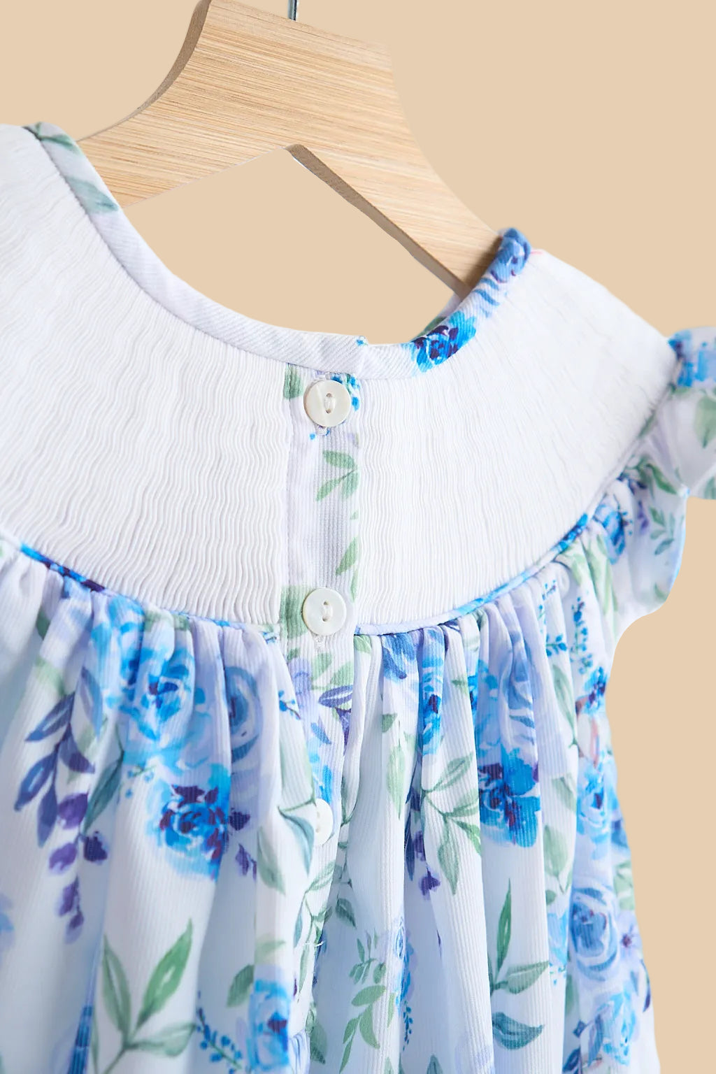 Blue floral hand-smocked kids dress with back button closure, close-up back view