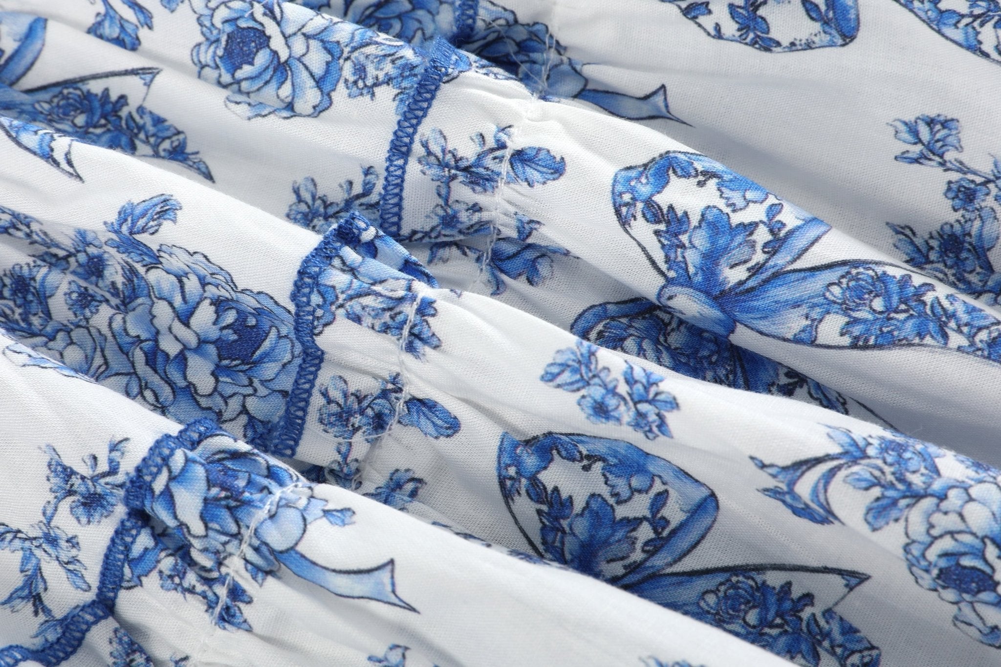 Blue and white bow-and-flower print sundress with contrast tier stitching, fabric close-up