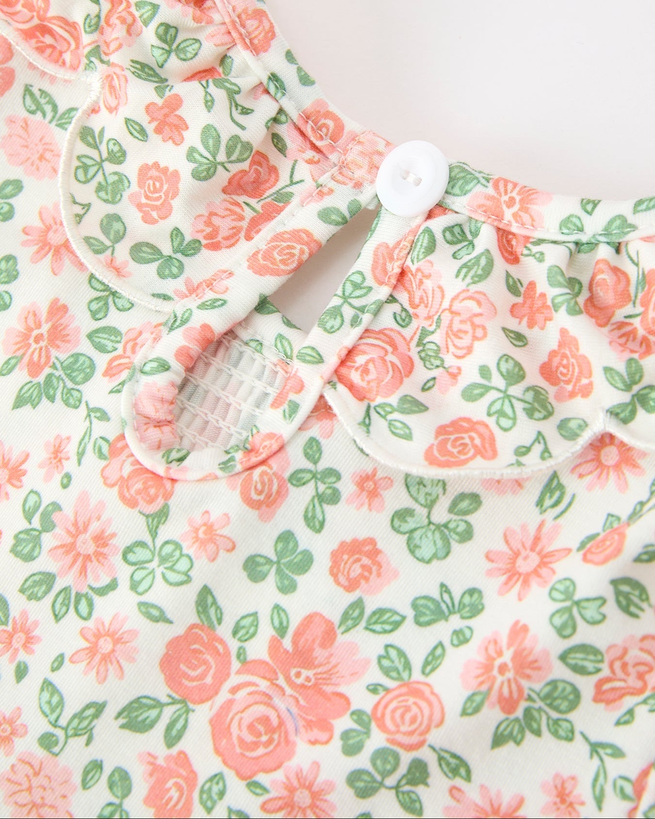 Blush floral kids dress with back keyhole and single-button closure, neckline close-up