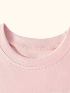 Blush pink kids dress with round neckline and short gathered ruffle sleeves, neckline close-up