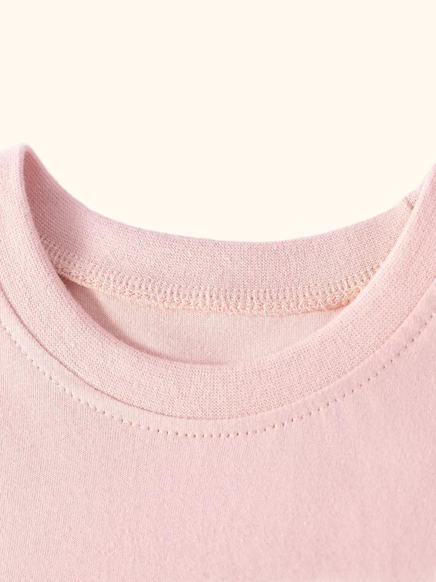 Blush pink kids dress with round neckline and short gathered ruffle sleeves, neckline close-up