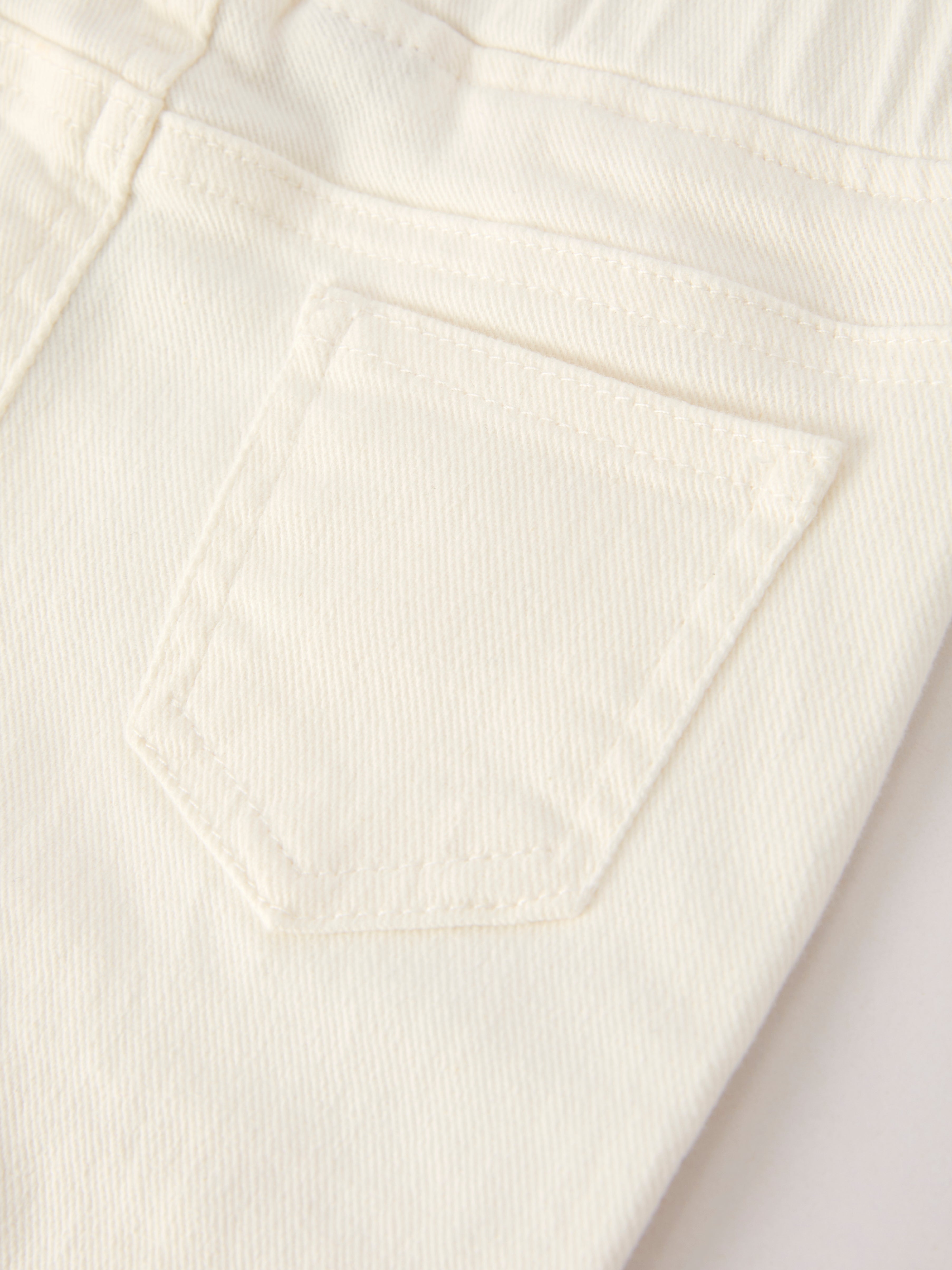 Ivory kids denim pants with stitched back patch pocket and elastic waistband, back pocket close-up