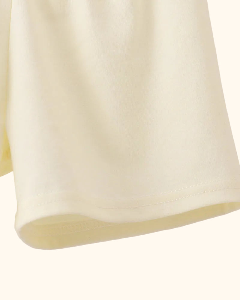 Cream kids pull-on shorts with clean hem finish, close-up view
