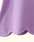 Purple kids top with rounded scalloped bottom hem, close-up detail view