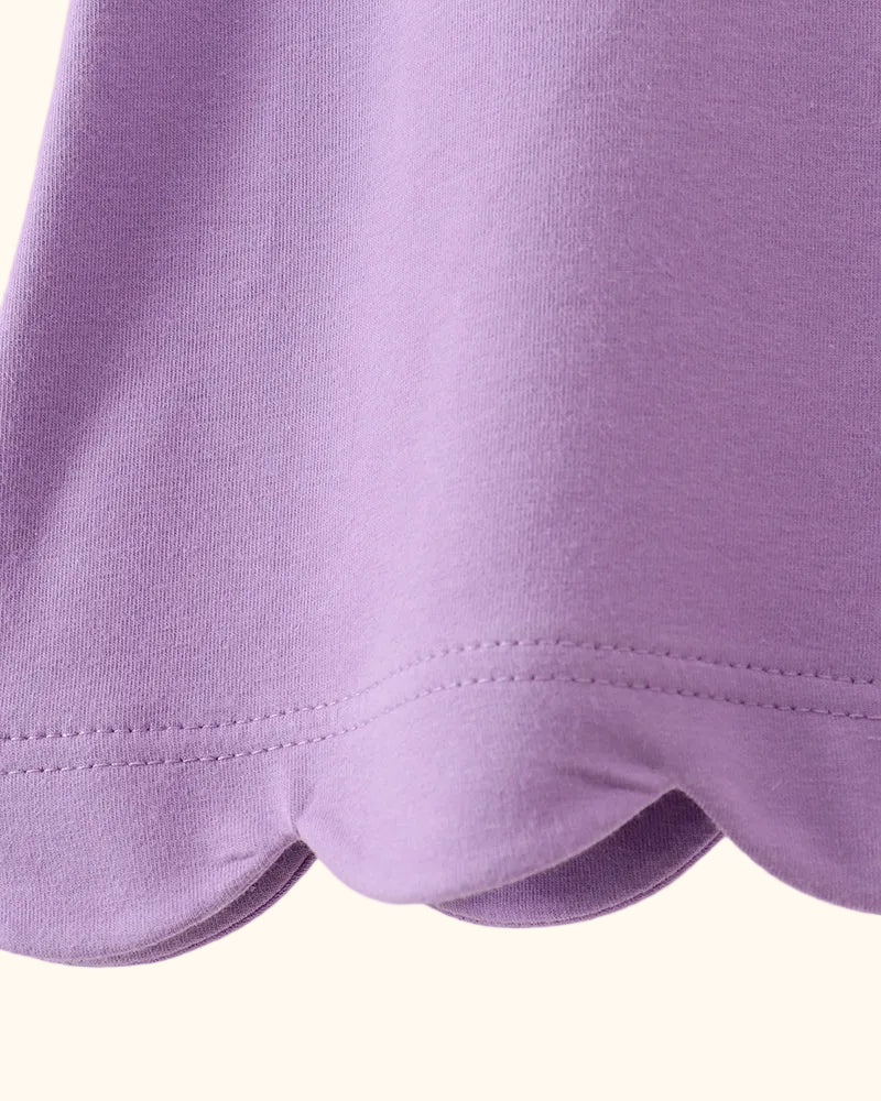 Purple kids top with rounded scalloped bottom hem, close-up detail view