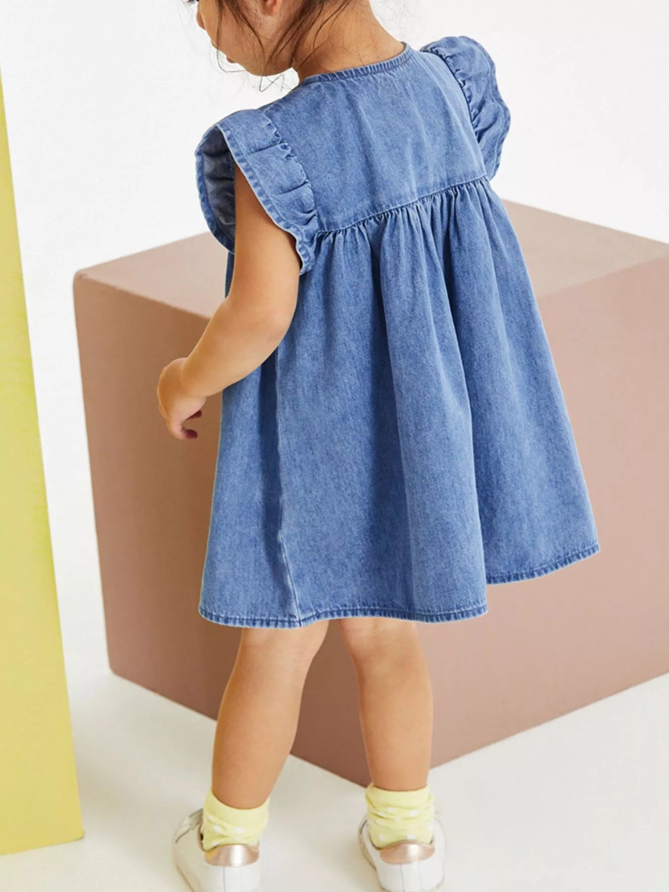 Denim kids A-line dress with flutter sleeves and gathered silhouette, back model view