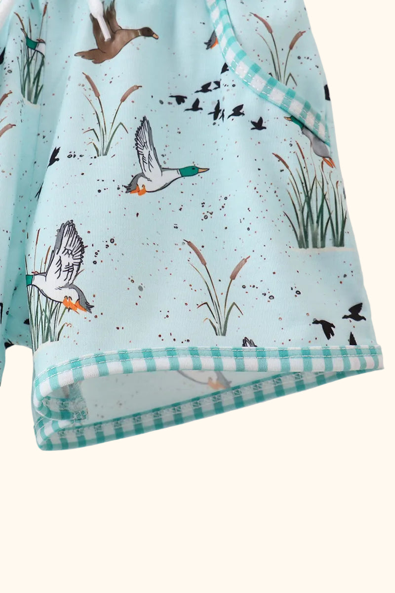 Green duck print kids shorts with gingham hem trim, close-up view