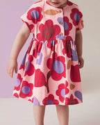 Pink kids floral print dress with oversized red flowers, worn by child, front lifestyle view