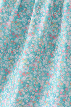 Green floral kids dress with tiny multicolor flower print, fabric close-up view