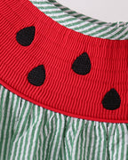 Red smocked watermelon yoke with black embroidered seed details, close-up view