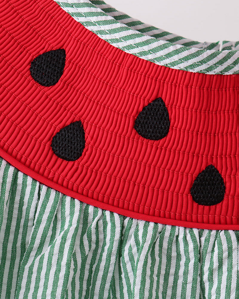 Red smocked watermelon yoke with black embroidered seed details, close-up view