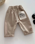 Khaki kids tapered trousers with elastic waist and graphic back patch pocket, back product view