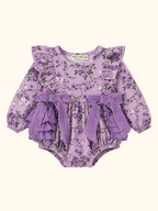 Lavender floral baby romper with ruffled shoulders, twin waist bows and long sleeves, front view