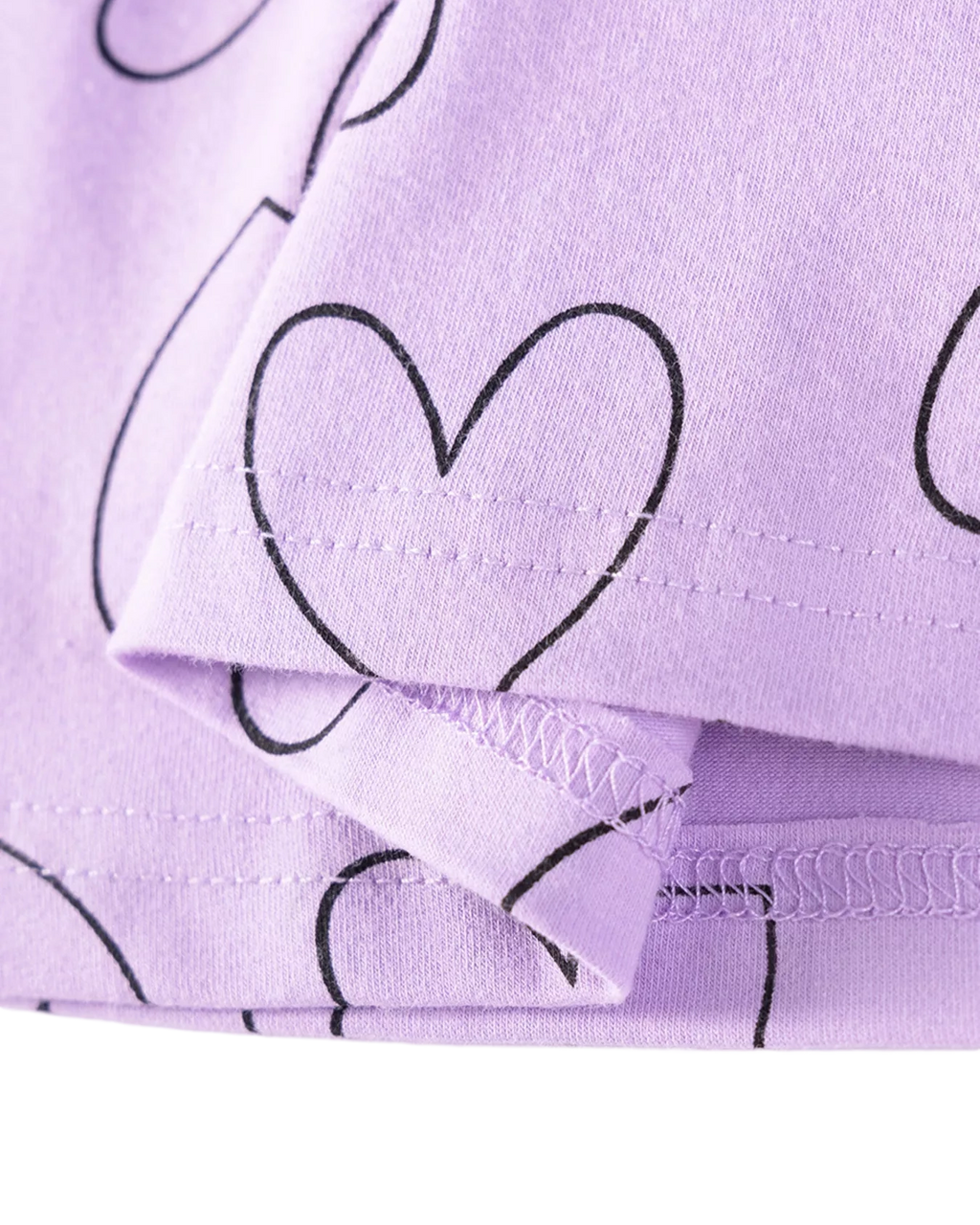 Lavender kids heart print dress with black outline hearts, fabric and hem close-up
