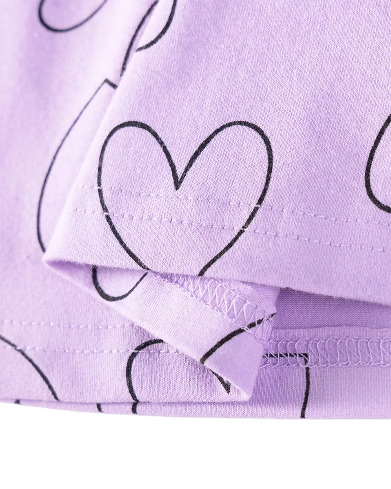 Lavender kids heart print dress with black outline hearts, fabric and hem close-up