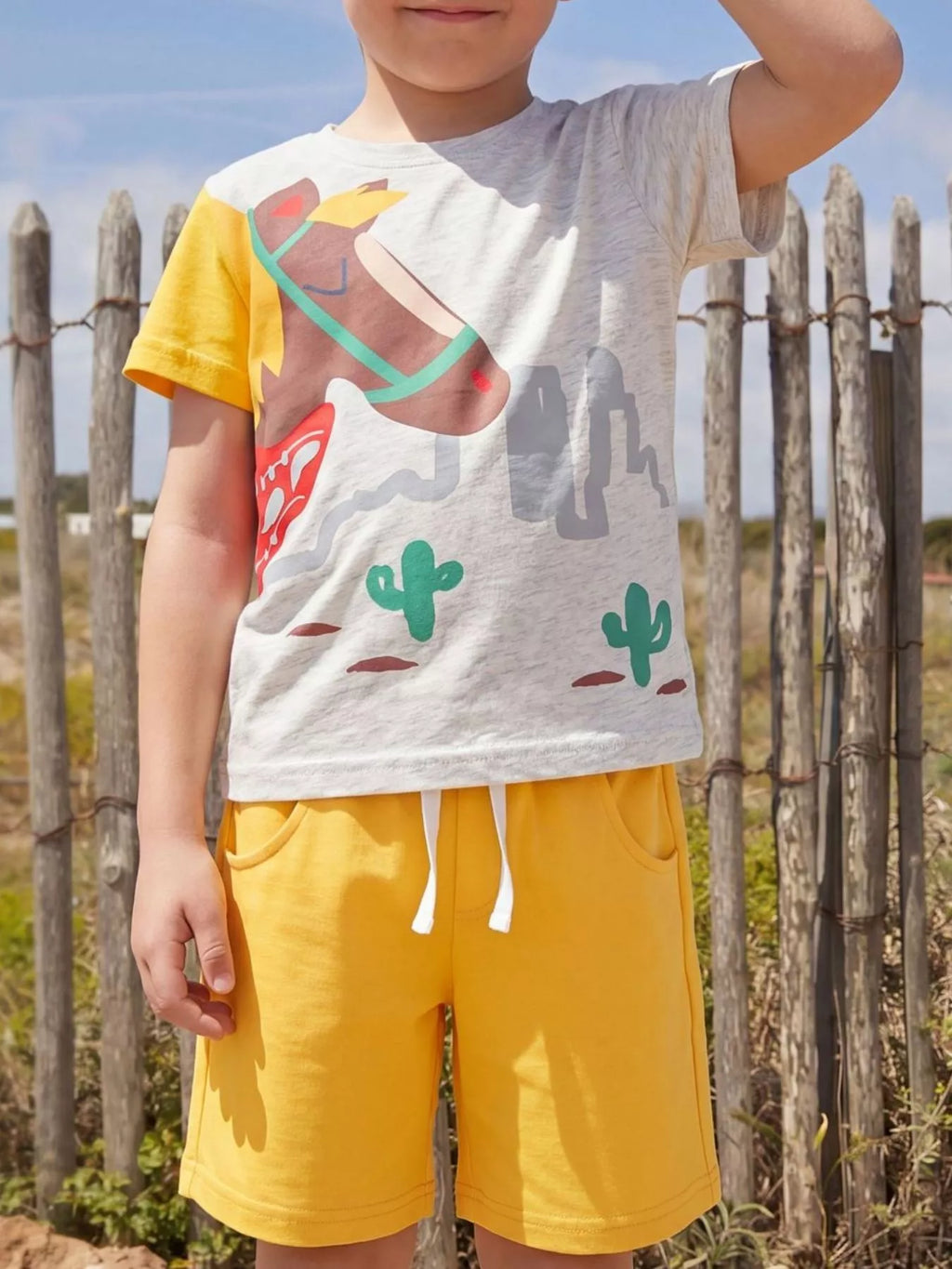 Light gray kids horse graphic tee and yellow shorts set, modeled front view