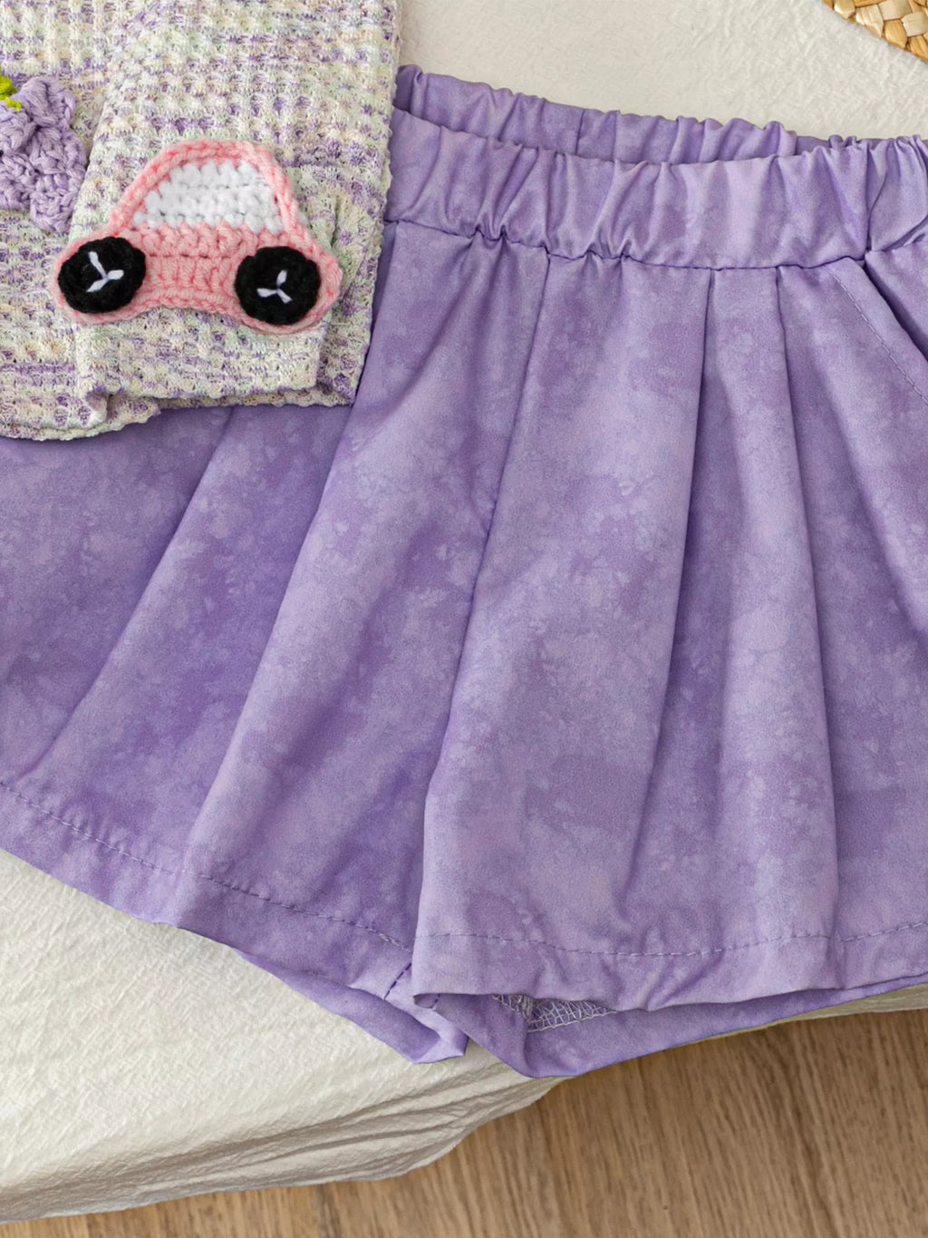 Light purple baby pull-on shorts with elastic waistband and subtle tonal pattern, close-up view