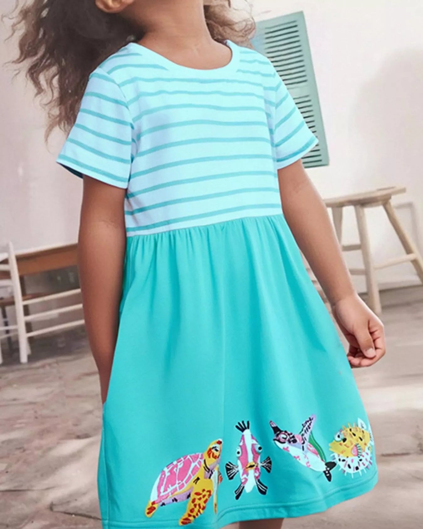 Mint blue kids striped turtle and fish embroidered dress worn by child, front lifestyle view
