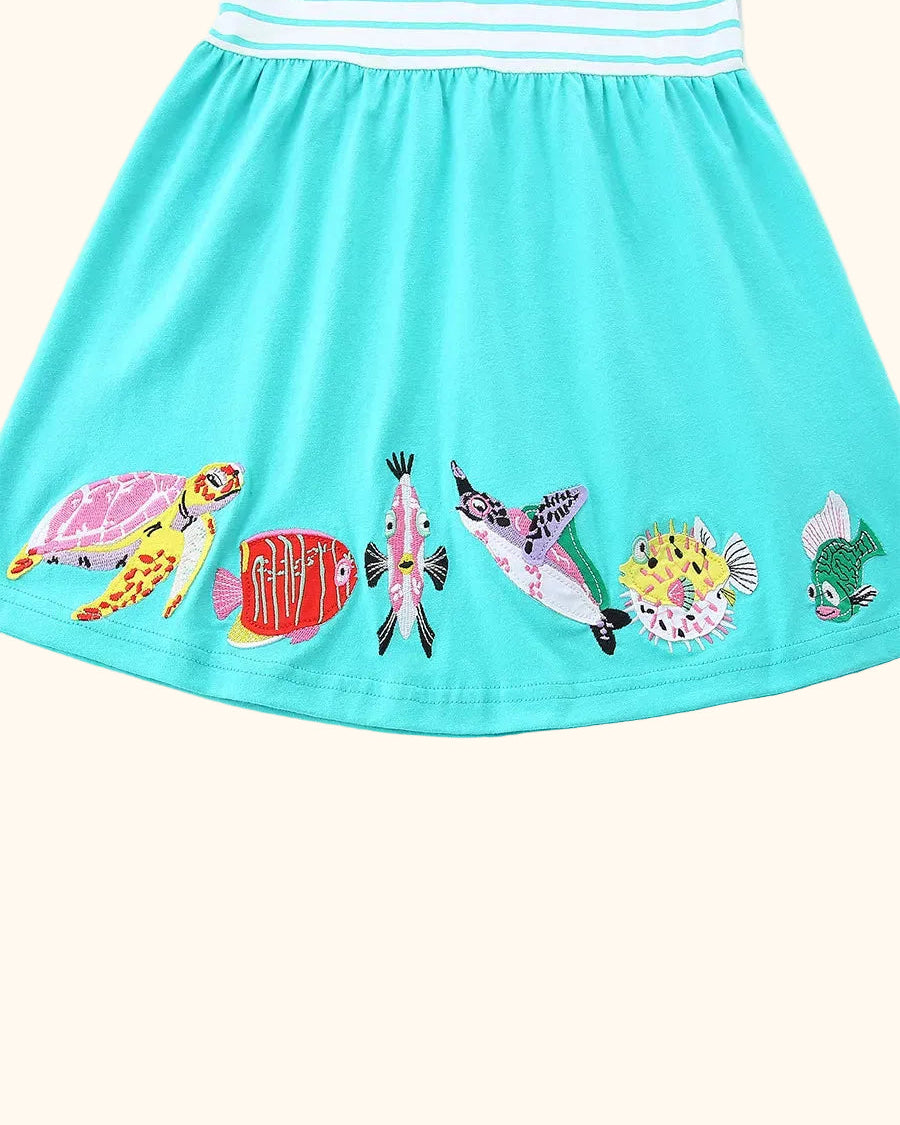 Mint blue kids dress with colorful embroidered turtle and fish along hem, detail view