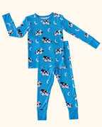 Bright blue kids cow print bamboo pajama set with crescent moons and stars, front flat-lay view