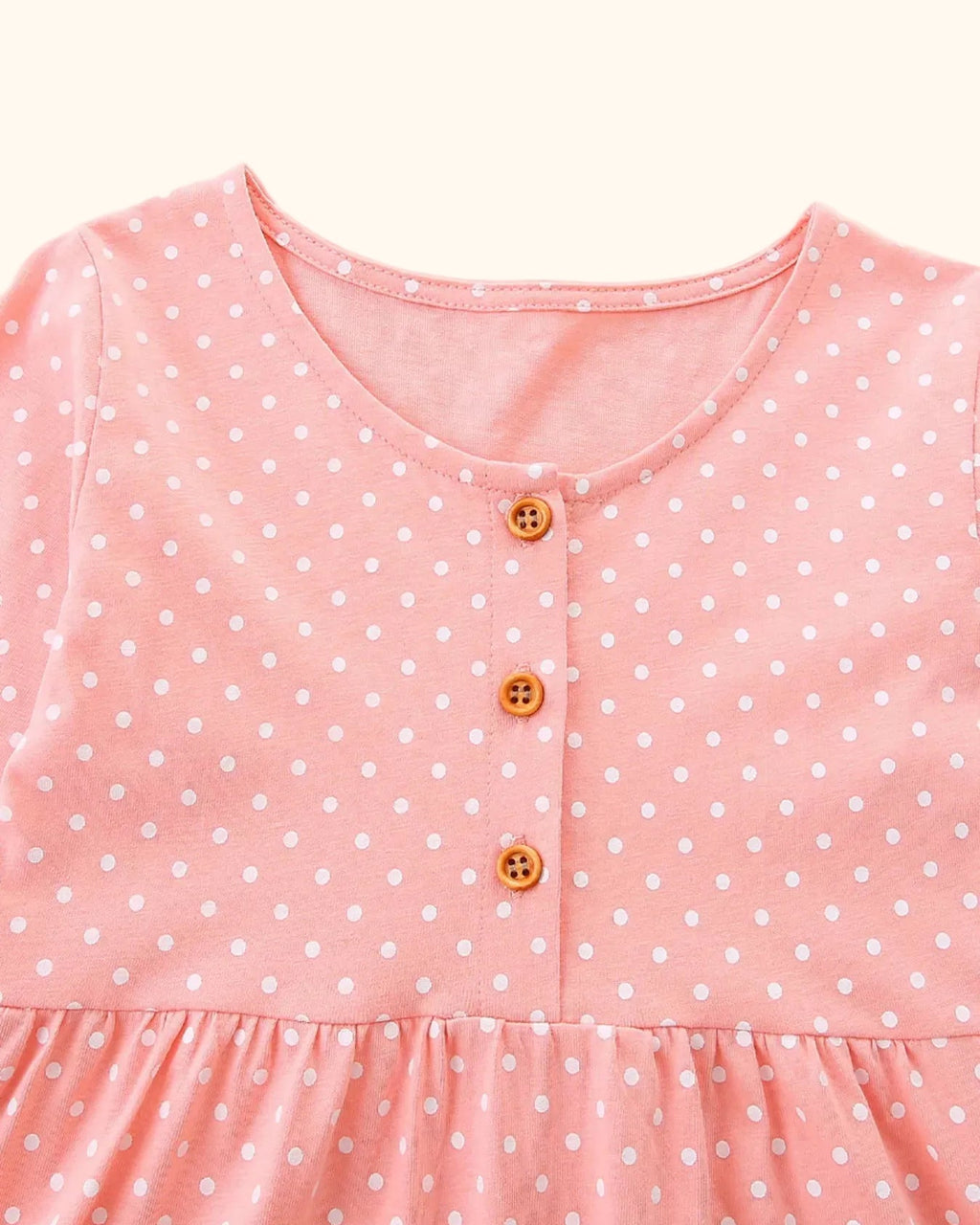 Pale blush kids polka dot dress with round neck and three-button placket, bodice close-up